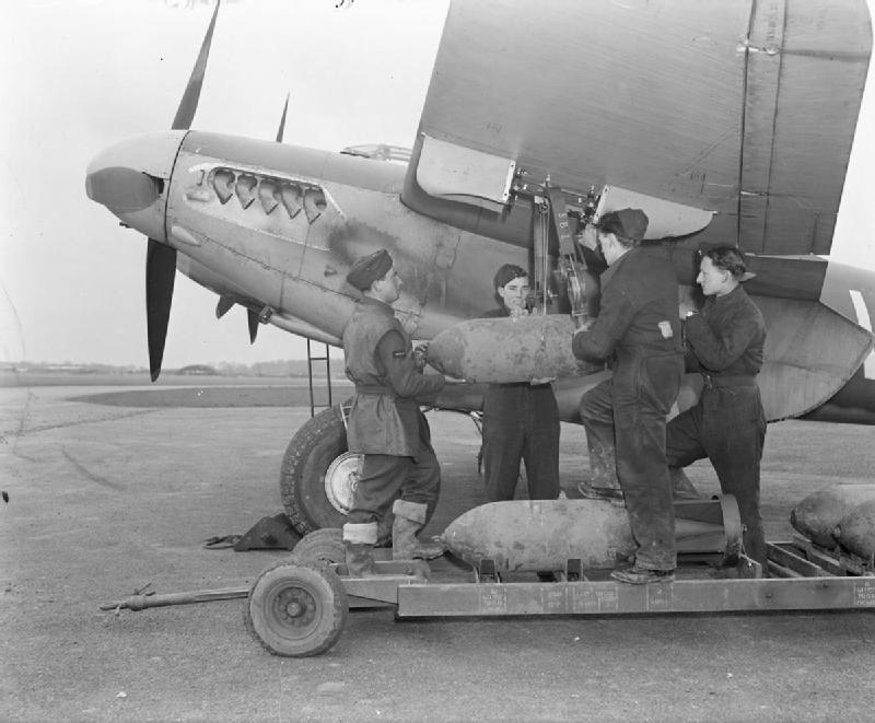 Armourers hand-winch a 500-lb MC bomb to the wing loading-point on De Havilland Mosquito FB Mark VI, MM403 'SB-V', of No. 464 Squadron RAAF at Hunsdon, Hertfordshire.